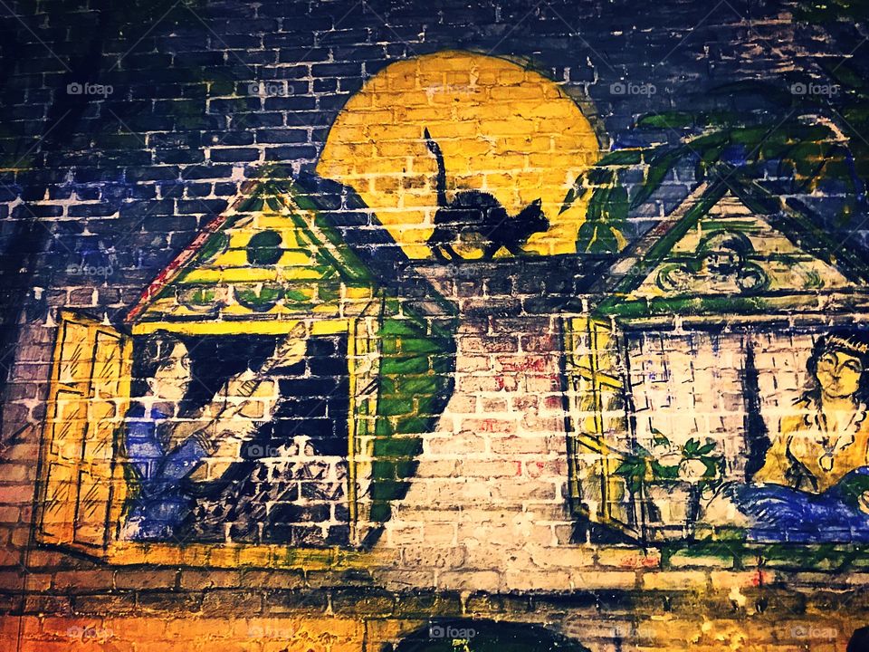 Black cat against moon painted on brick wall