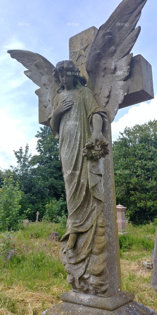 Victorian stone angel on grave in graveyard on summer day