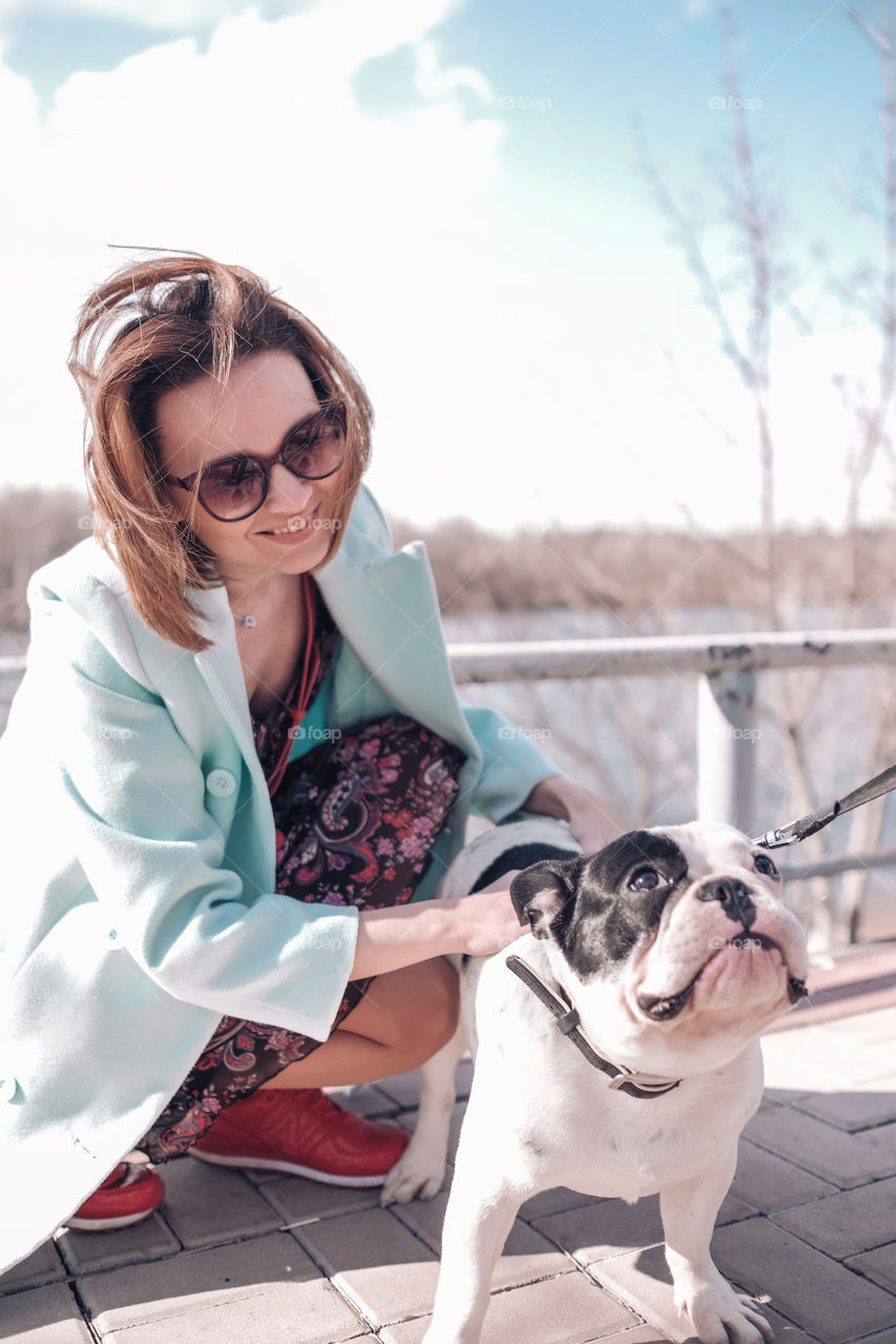 Smiling woman walking with dog in spring