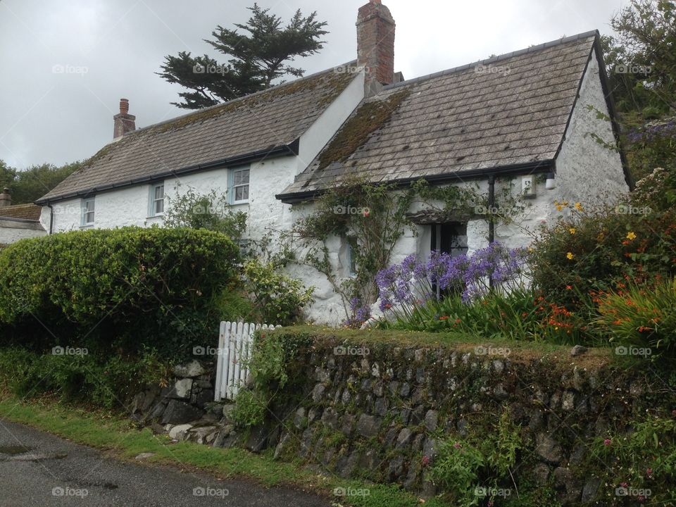 English cottage in Cornwall. In the coastal village of Port Hallow. With nice flowers near white wooden gate.