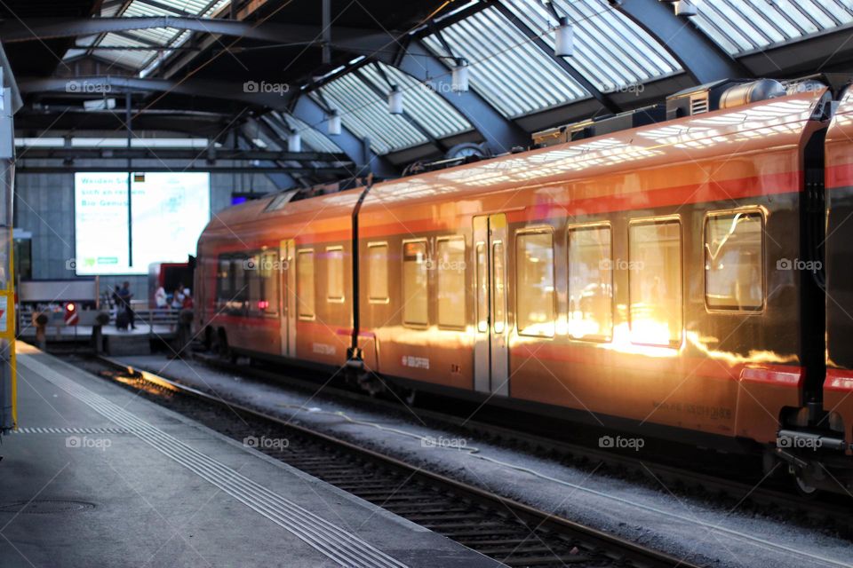 Red passenger train in the station at sunrise 