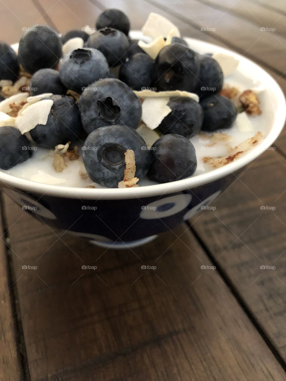 Blueberries on a bowl of coconut granola with almond milk 