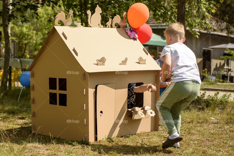 Children play with a cardboard house.  Children's fun