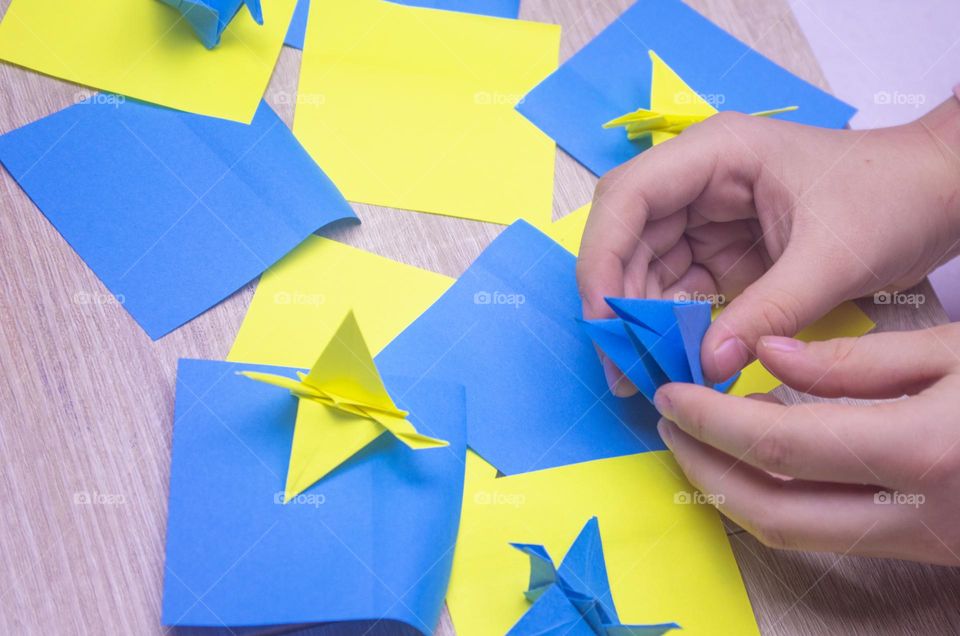 child folds paper cranes