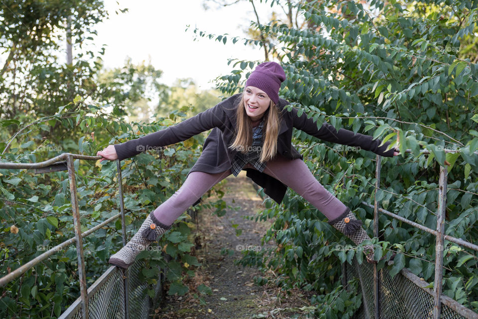 Millennial woman laughing and playing on a bridge