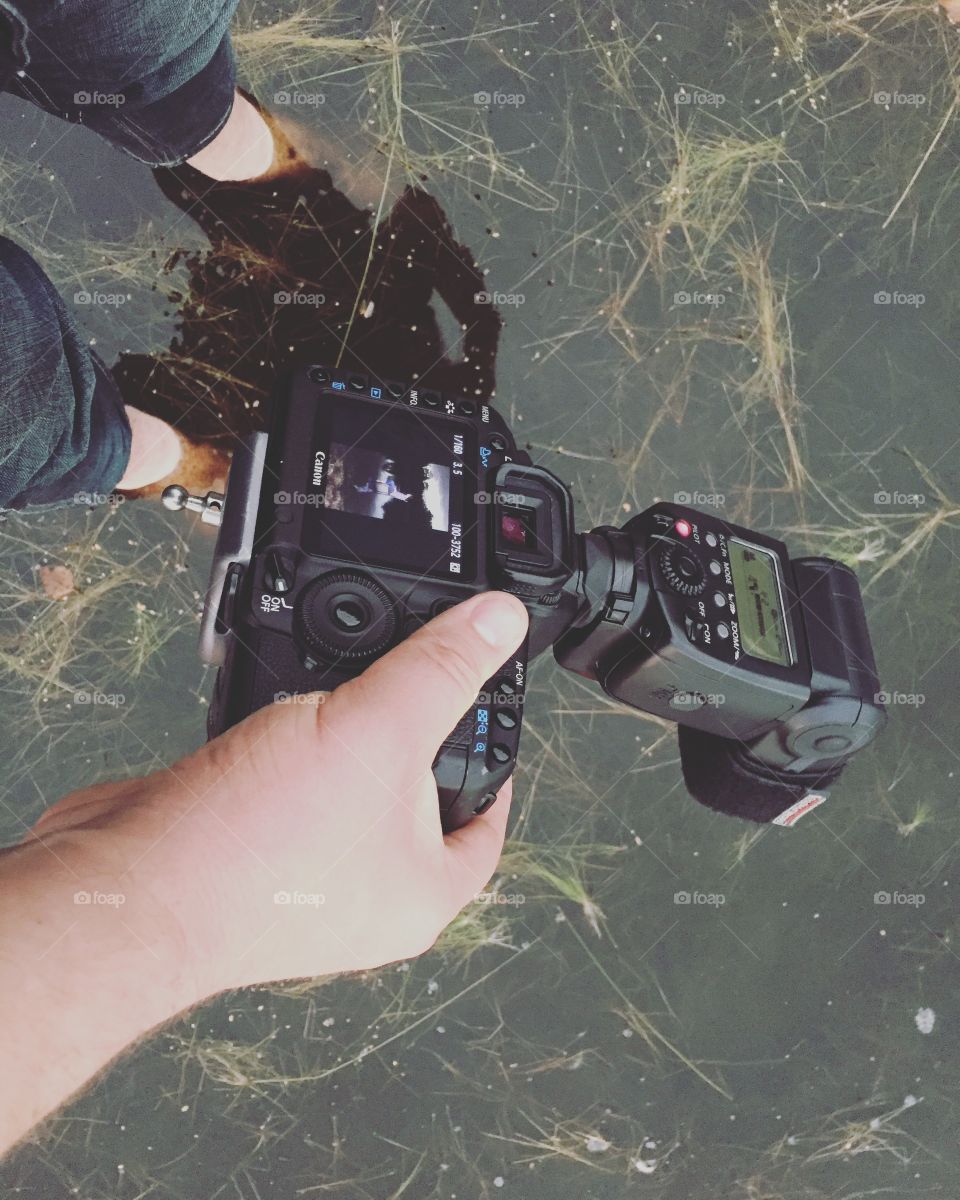 Photographer taking pictures while staying ding with his feet in the water