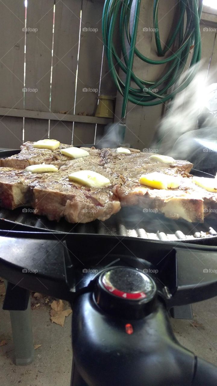 T bone steaks on an electric grill seasoned with spices and butter  🧈 on a patio in Citrus Heights california