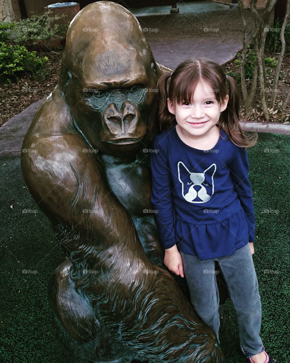 Cute girl standing near animal statue