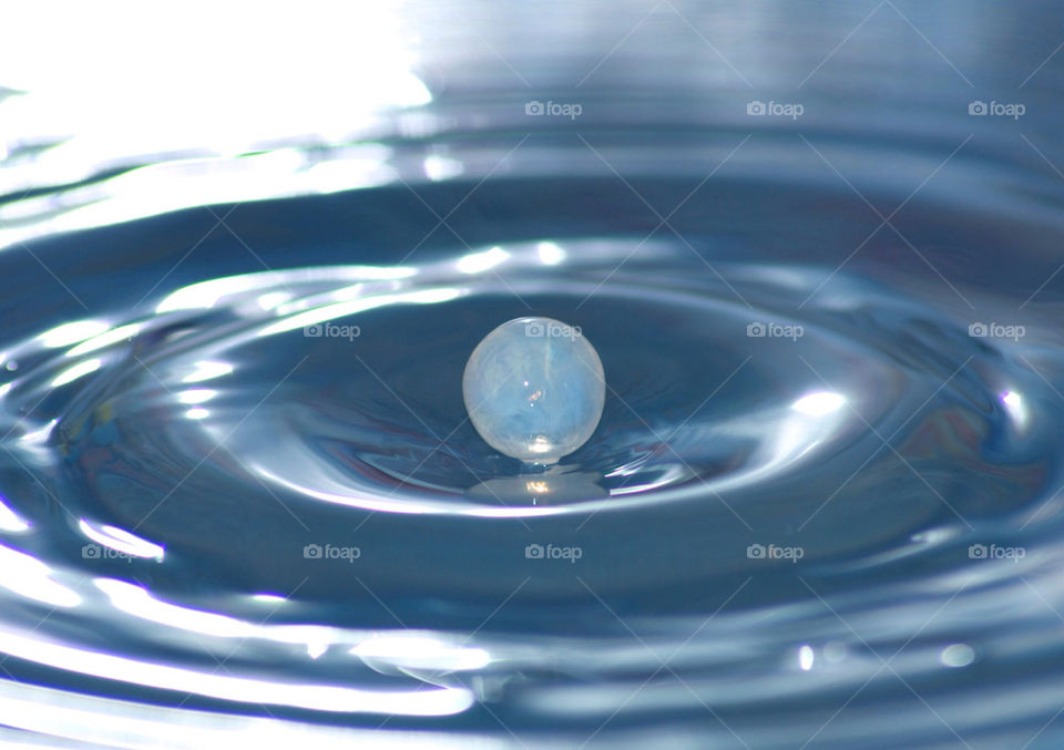 A drop of milk dripping into a pan of water.