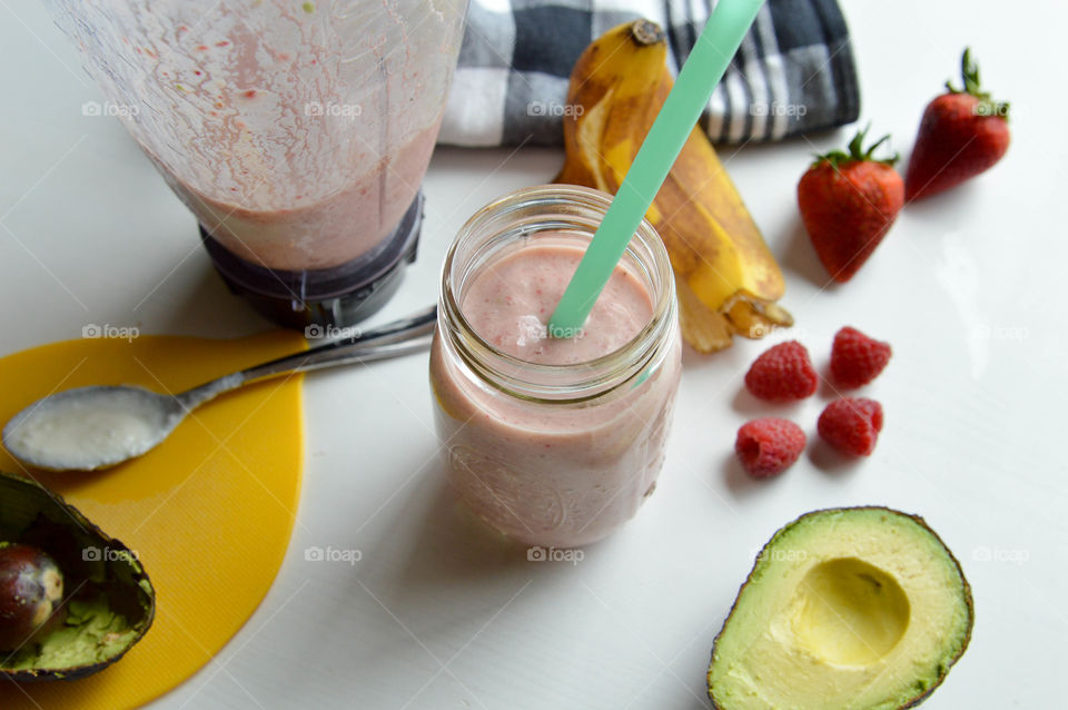 Fresh fruit smoothie in a glass with banana peel, avocado, raspberries and strawberries