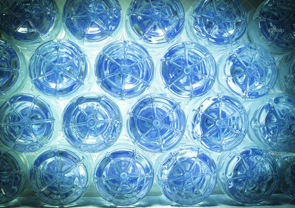 Rows of water in plastic bottles bottom on blue background