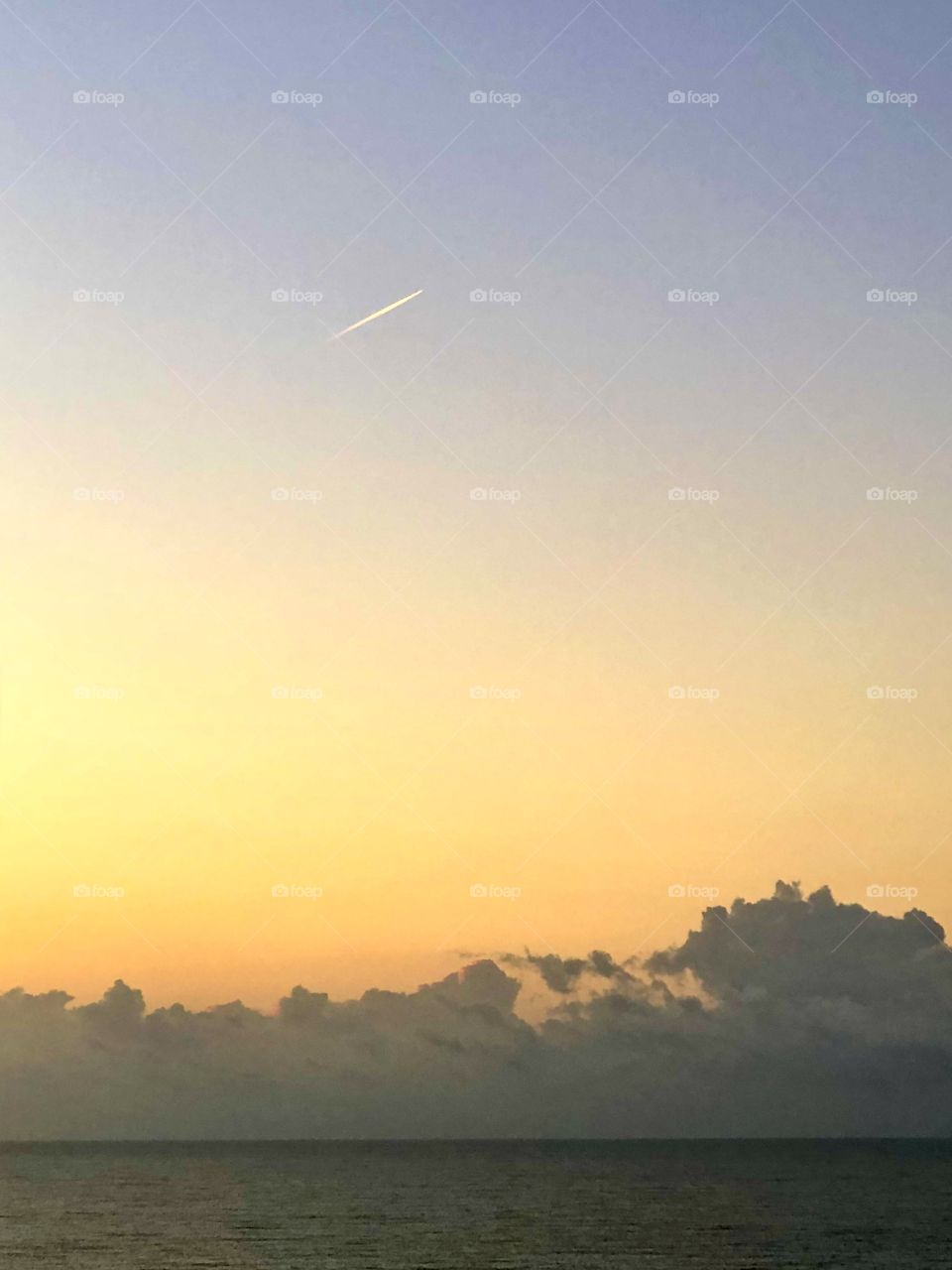 Jet trail over sunrise at the Gulf of Mexico 