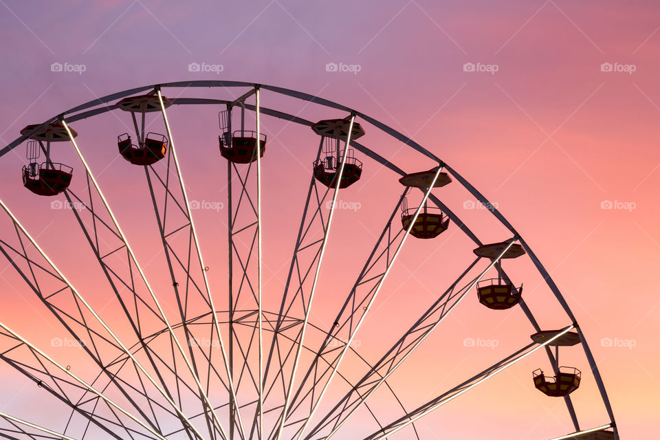 Ferris wheel silhouette against pink sunset