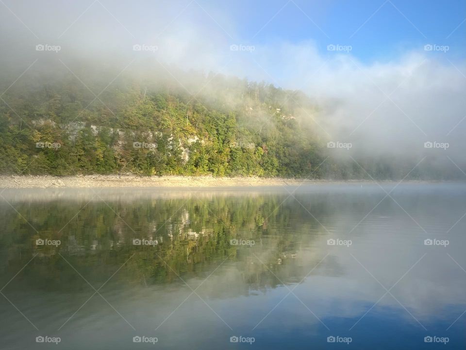 Beautiful, Misty morning on the lake as the sun starts dispersing the fog 