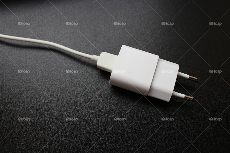 White USB cable and charger on a black cardboard background