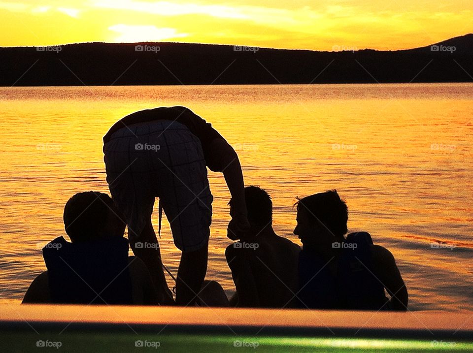 Boys fishing at sunset silhouette lake. Boys fishing on rowboat at sunset silhouette lake