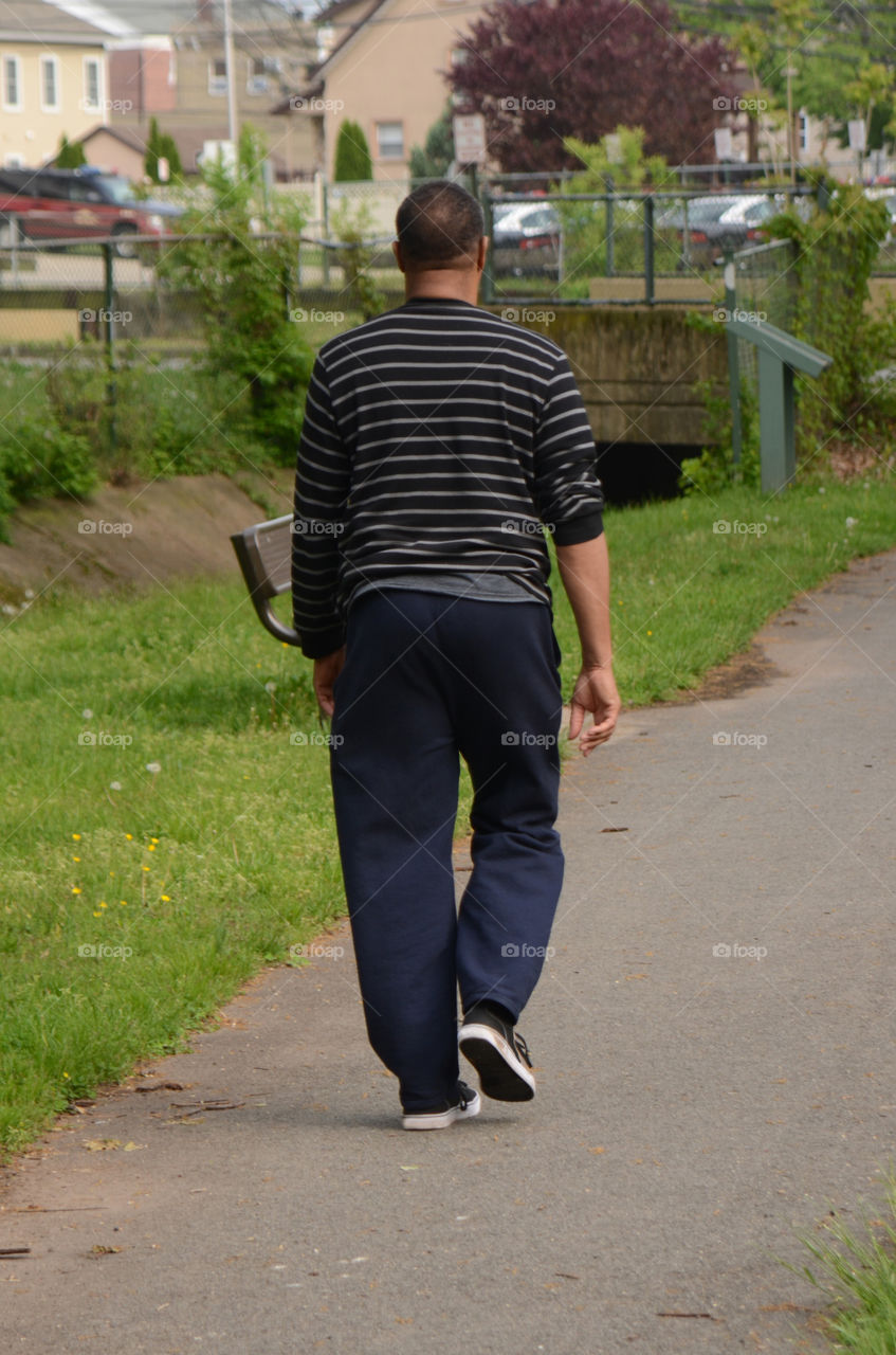 An older gentleman takes leisurely walk in the park to get some exercise.