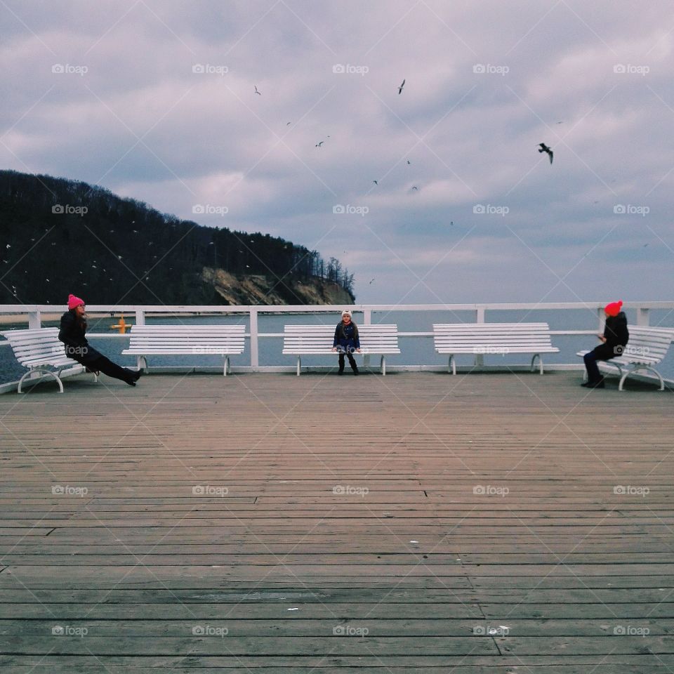 People relaxing on bench near sea