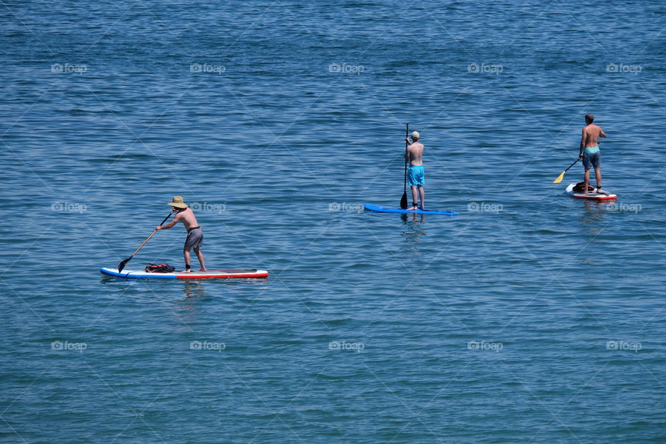 Three tourists paddleboarding.