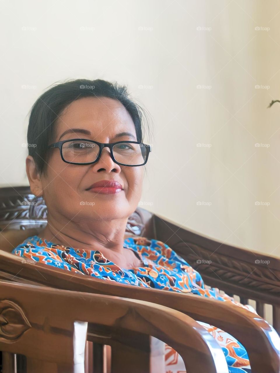 Close-up of woman in glasses sitting on chair at home