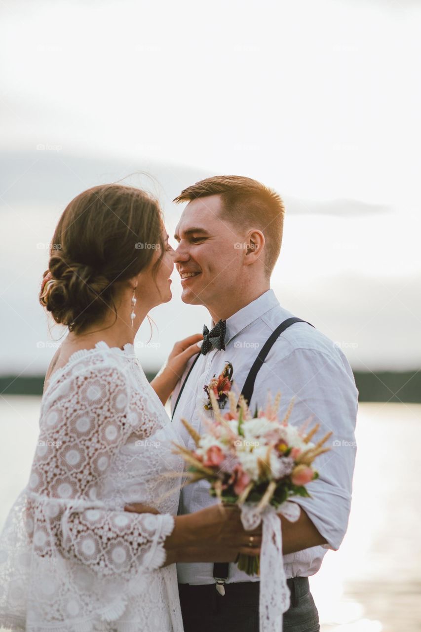 Happy newly married couple, smiling bride brunette young woman with the boho style bouquet with groom, close up portrait outdoors