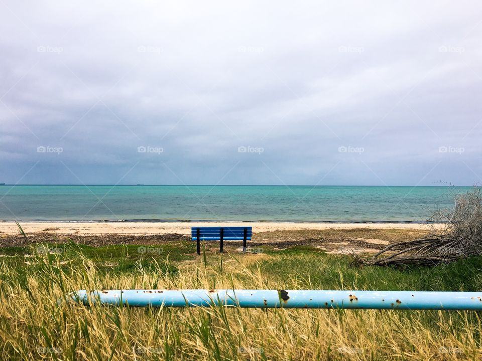 Aqua blue bench on the beach on the sea oats in a remote place