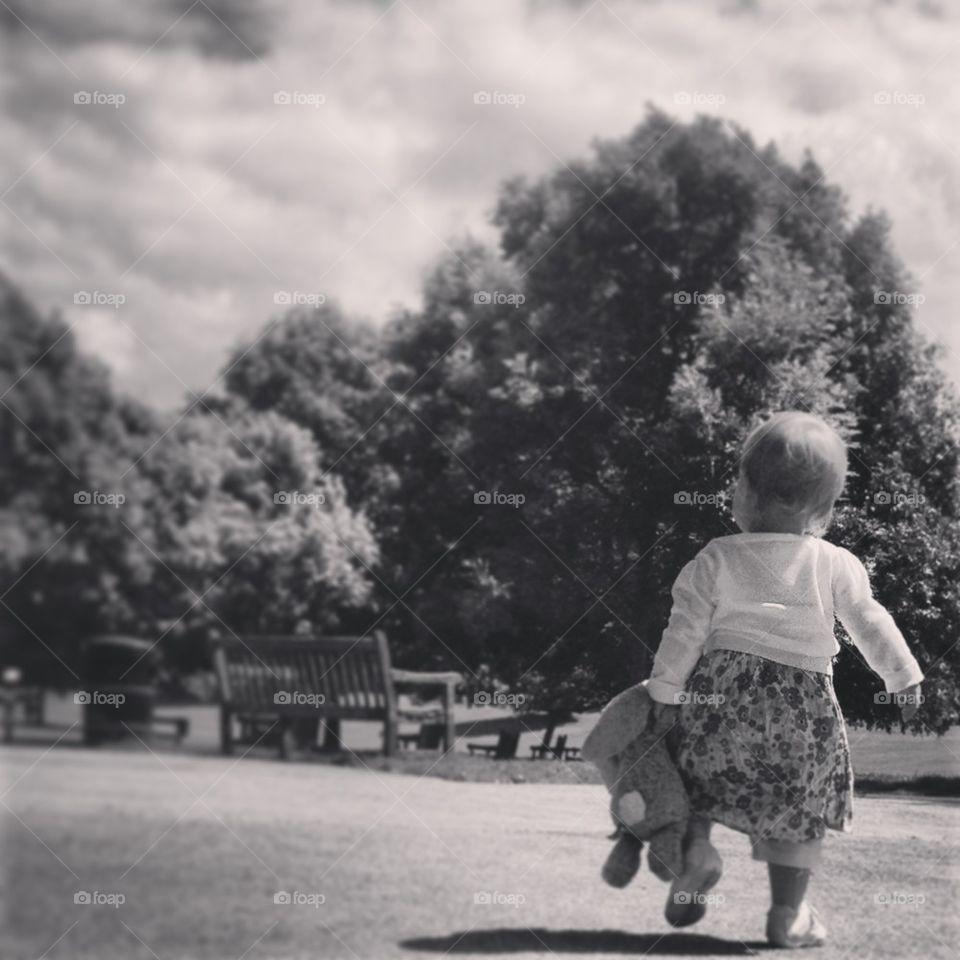 Baby in the park walking tall with toy rabbit