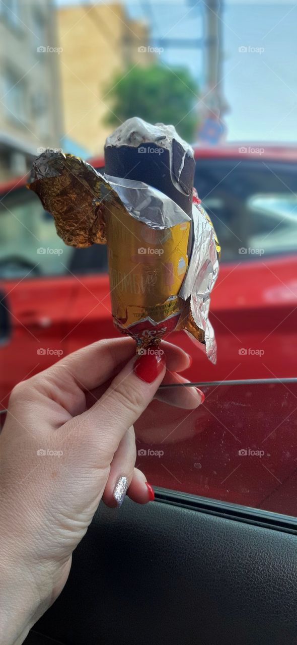 мороженное"московский пломбир" в руке девушки с красным маникюром  на фоне красного автомобиля