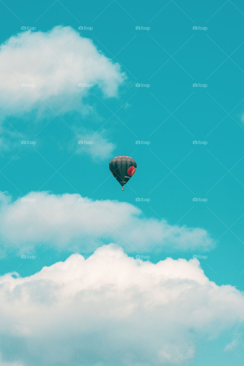 Hot-air balloon in flight at the sky among the clouds.