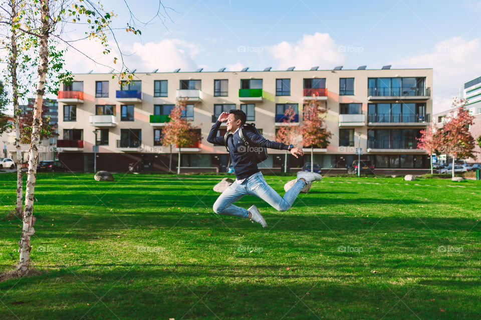 Young student is jumping up high with his school bag because he is feeling so excited for the new school year and ready to going back to school