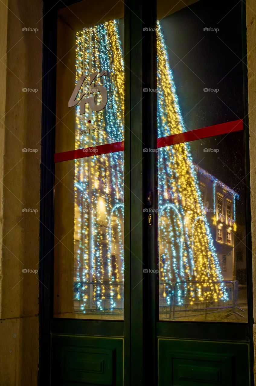 Christmas lights twinkling in the reflection of a window