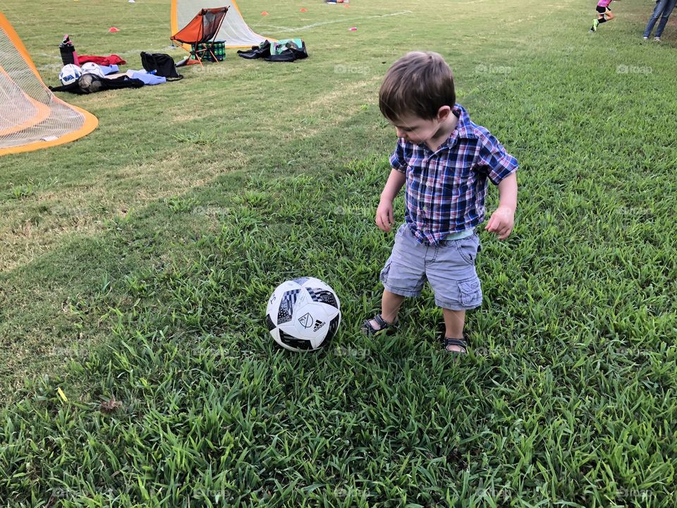Toddler kicking soccer ball. 