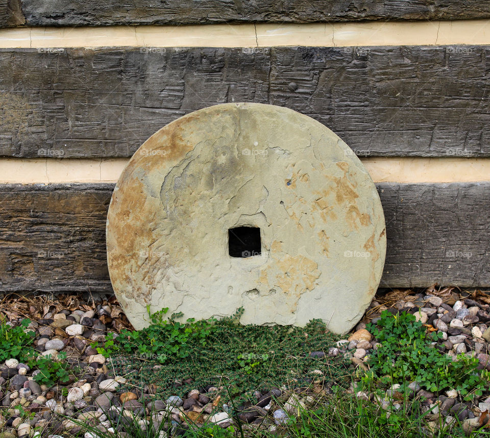 Antique mill stone against log wall 