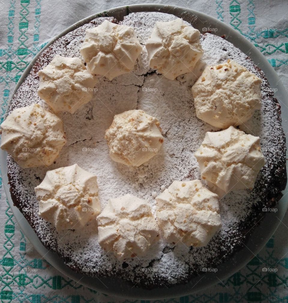 a closeup pic of a tasty and fresh homemade chocolate and pears cake with meringues on top just cooked