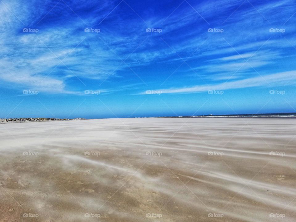 Wind moves sand on the beach.