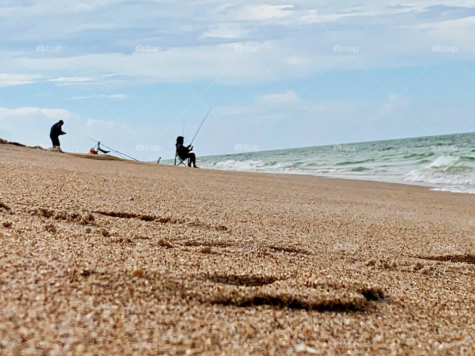 Fishermen on a seashore sand hill at the beach on vacation in the Atlantic Ocean.