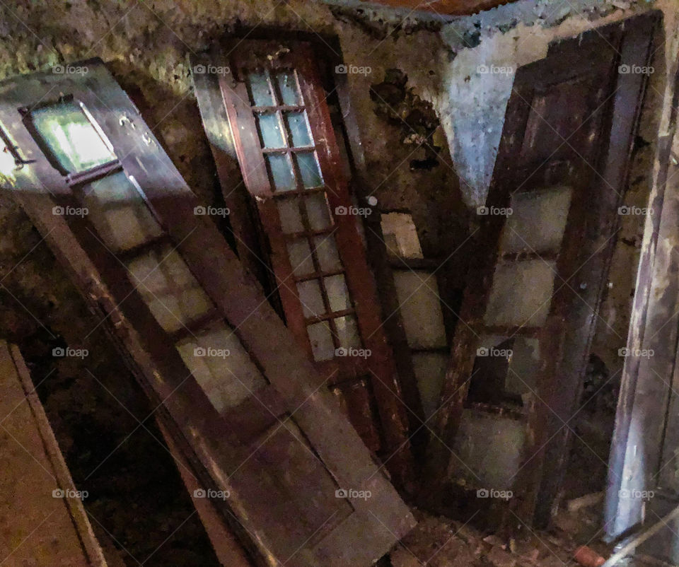 The doors - old wooden doors in a state of disrepair leaning against the wall in a darken store room. Some light spills in from a window off camera