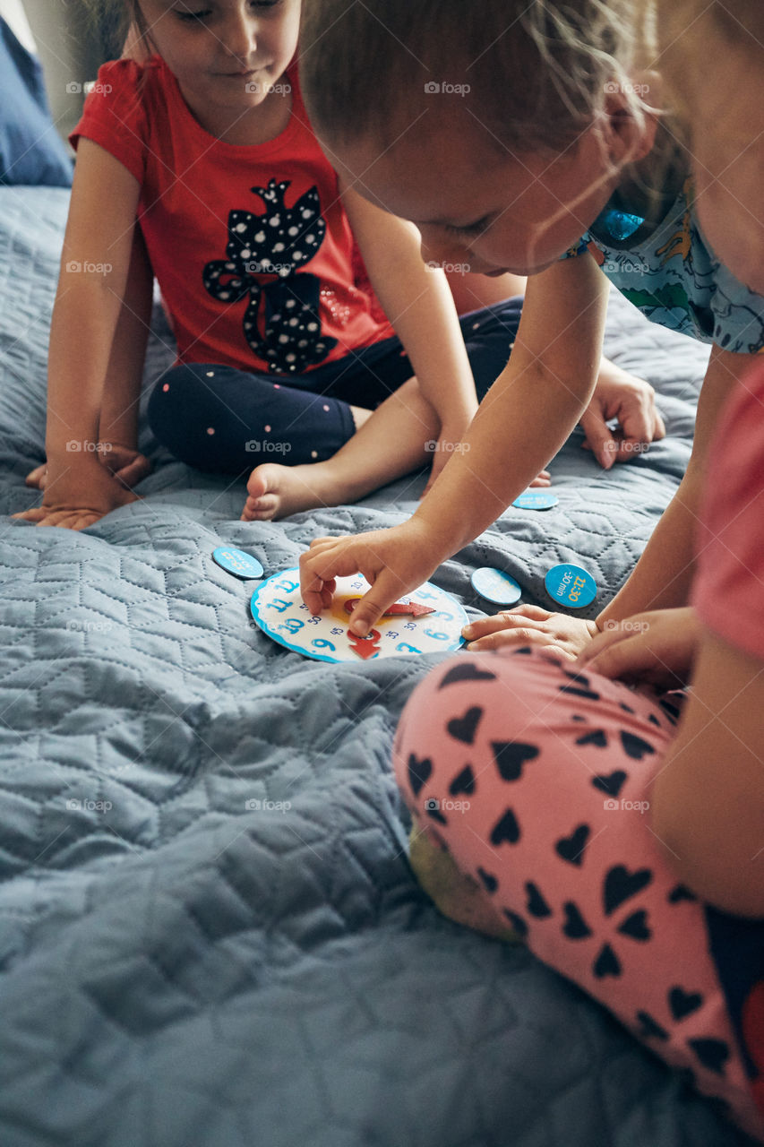 Kids learning how to tell time from clock and set the hands in the correct position. Teaching preschoolers tell time. Candid people, real moments, authentic situations