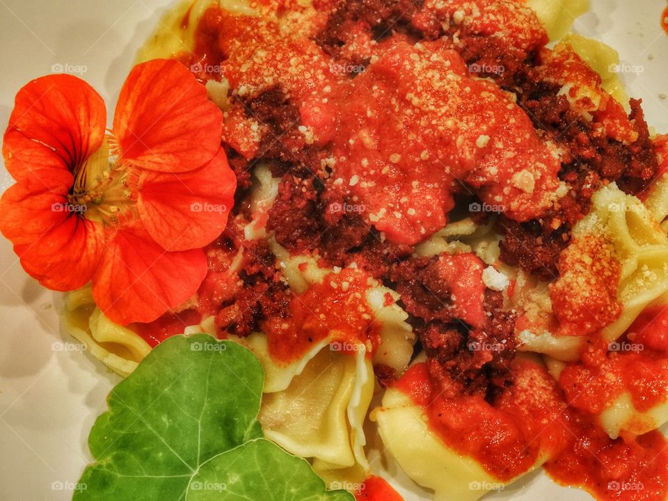 Tortellini With Chorizo And Nasturtium Flower Garnish. Fresh Pasta With Meat Sauce