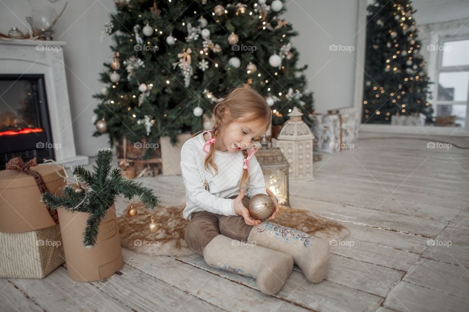 Little girl  in wool boots near Christmas tree 
