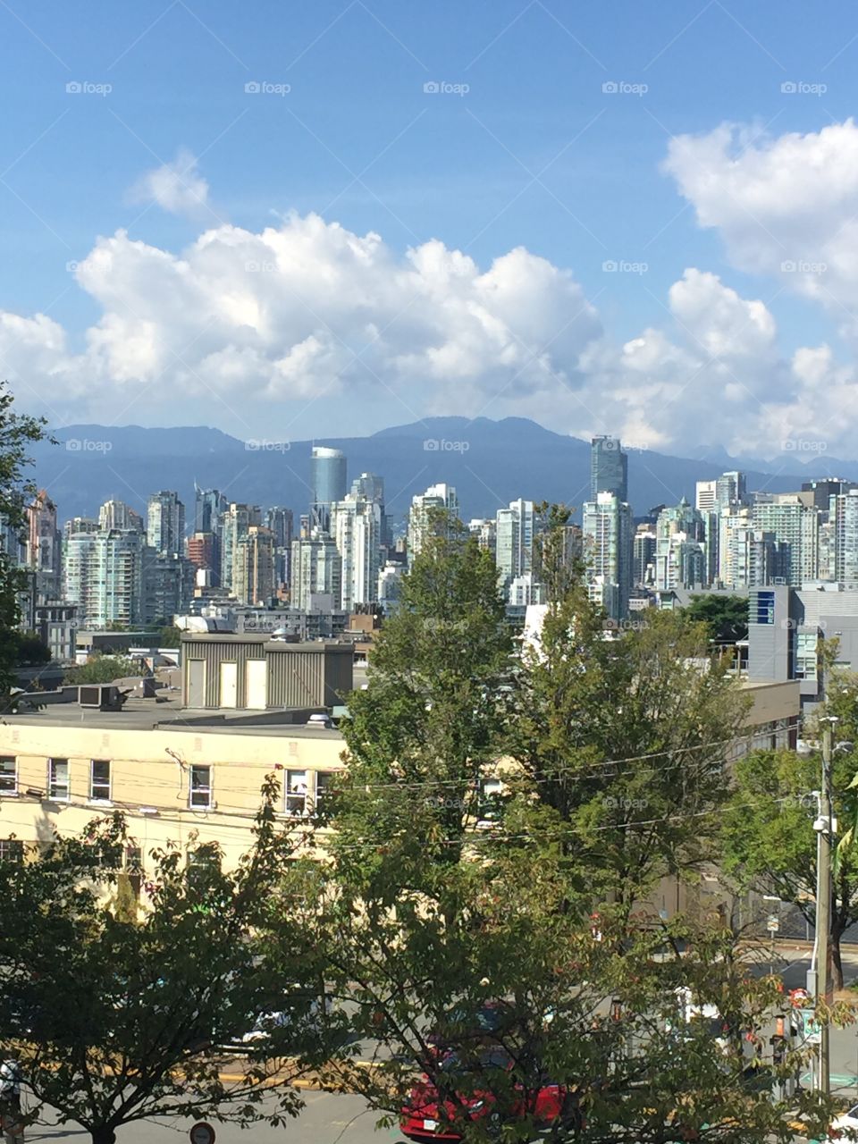 A slightly obstructed view of downtown with mountains in the distance in Vancouver, British Columbia.