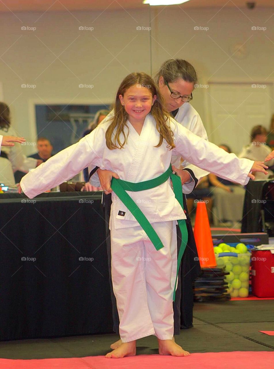 Woman wearing karate belt to smiling girl