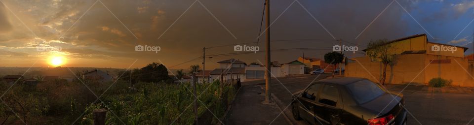 The sunrise, the storm clouds and the rainbow... A magical Golden Hour in a day of a small country city captured in a panoramic photo. Many weathers in a single moment.