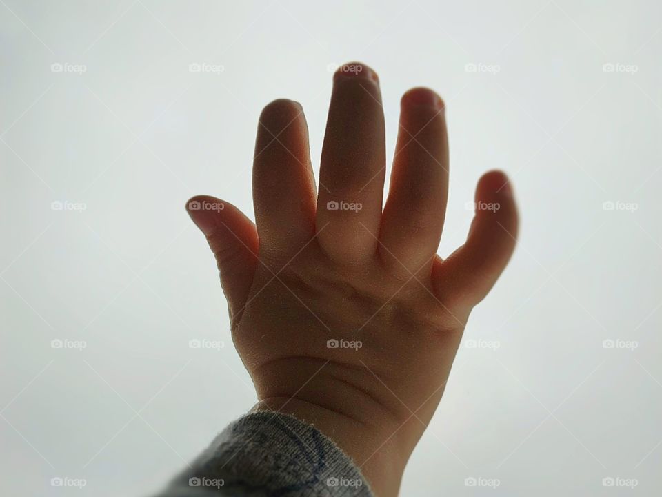 Child's hand on the glass against the sky
