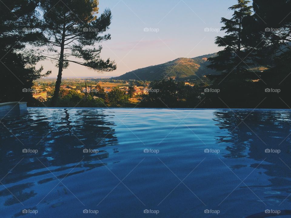 Infinity pool overlooking Mediterranean Sea. Gorgeous infinity pool overlooking the Mediterranean and the French village of Pegomas with trees mirrored on water. 