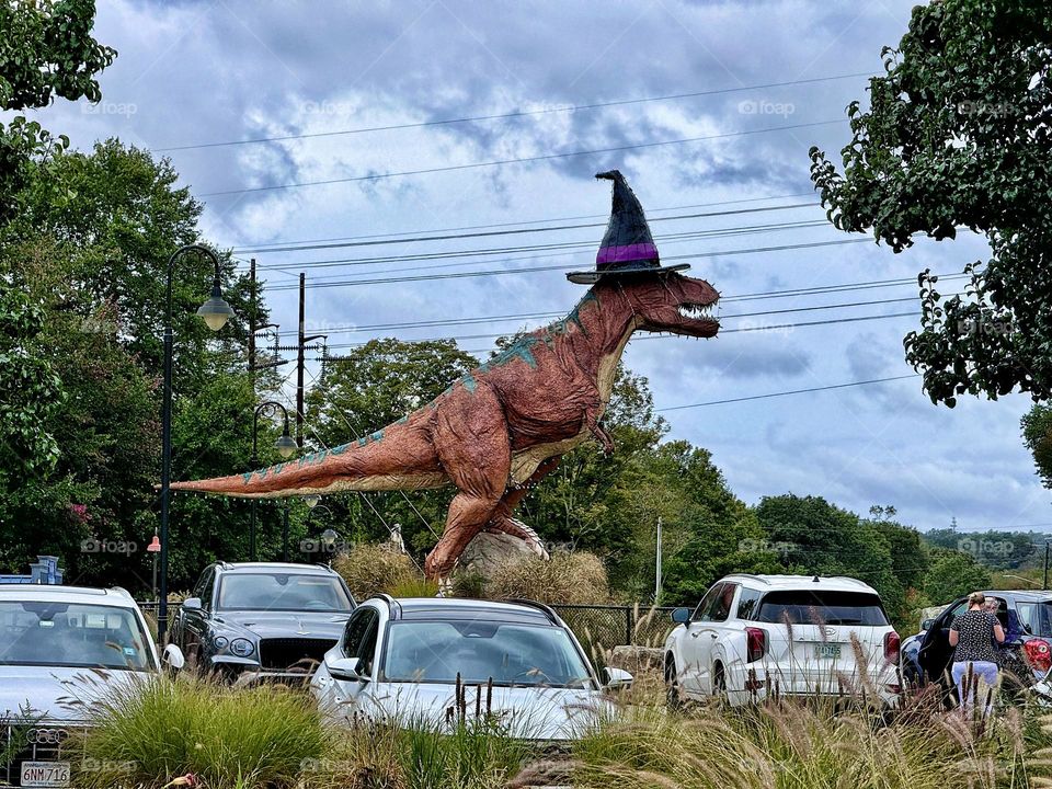 Dinosaur in a witches hat in a parking lot in New England 