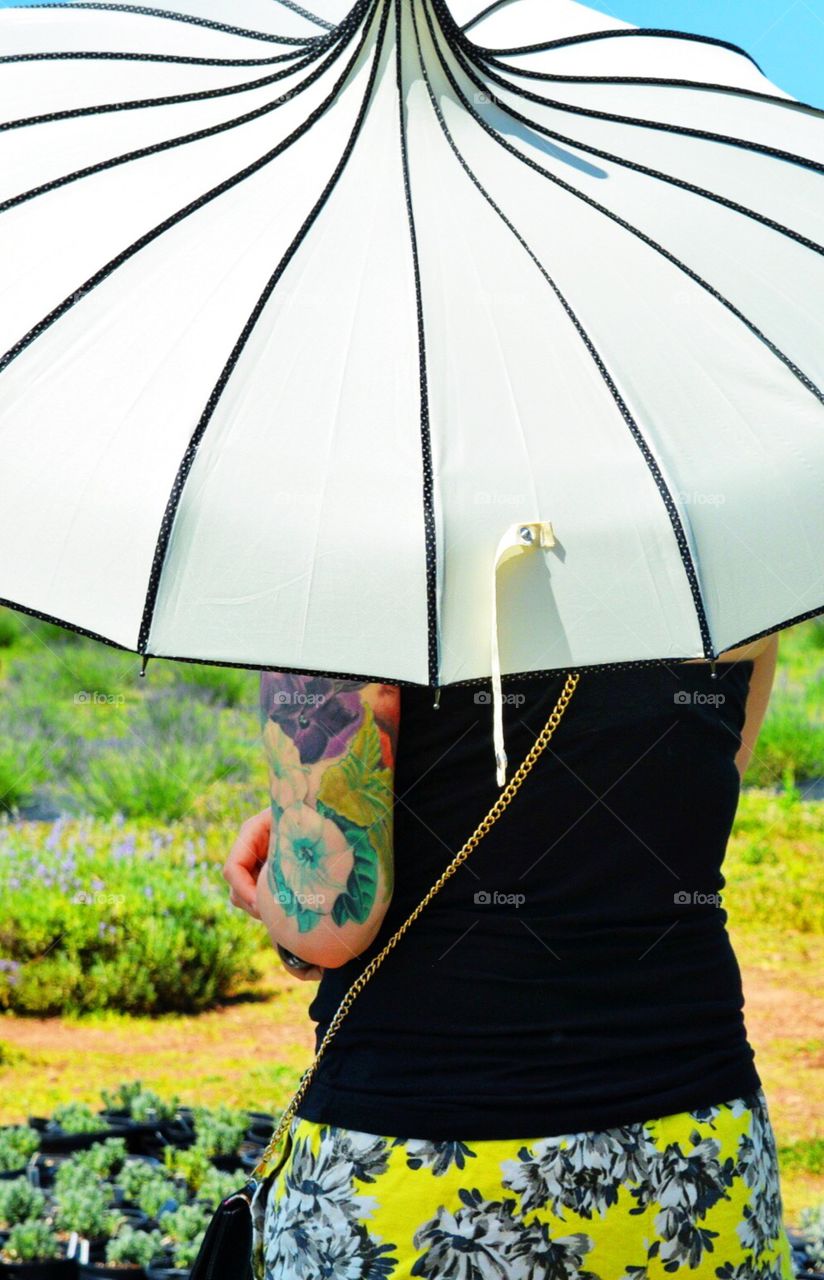 Colorful tattoo sleeve on woman with umbrella in a garden