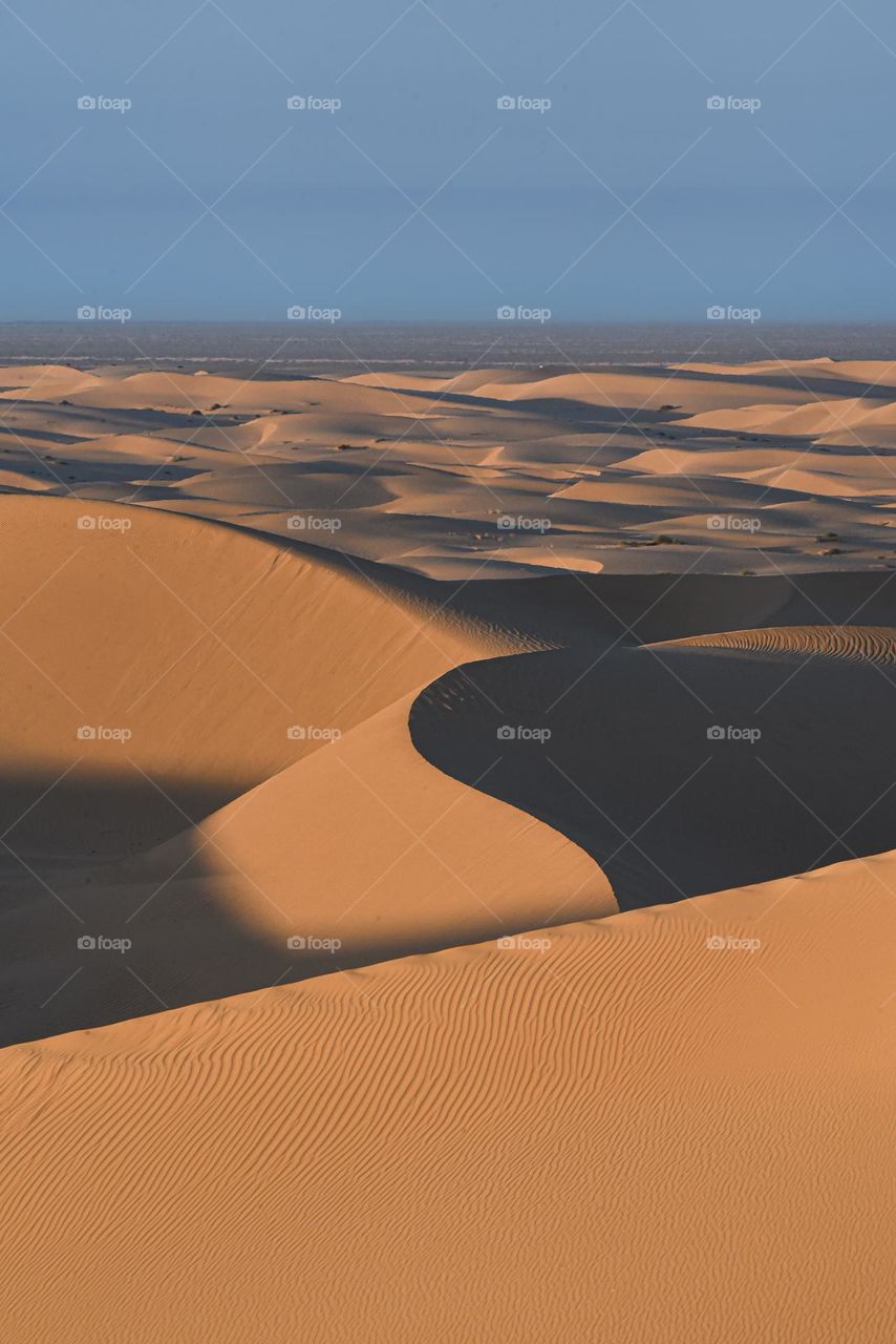 The light and shadows of the natural landscape of the desert. A natural background and beautiful scenery with a clear blue sky along the horizon