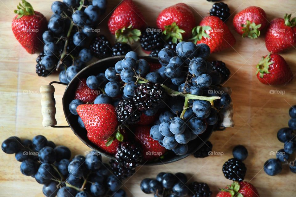 A collection of all our favorite fruity tasting and sweet berry fruits lay out on a wooden cutting board.