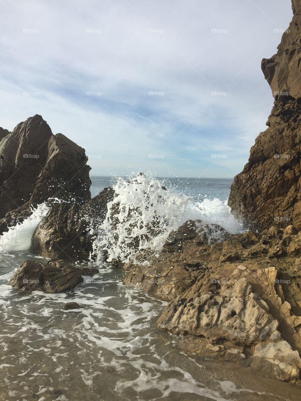The rocky beach shore, water splashes on rocks. 